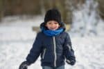 Cute little young boy in winter clothes playing in the snow