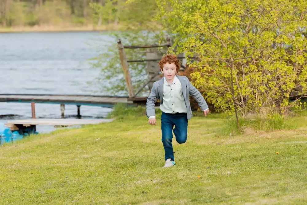 Cute little young boy running near lake