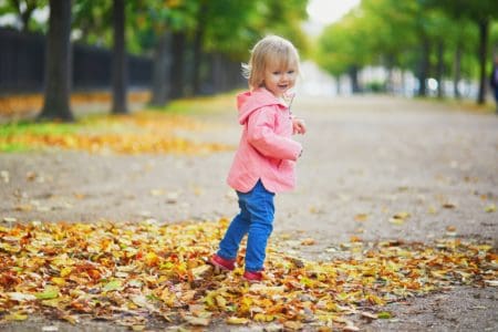 Adorable cheerful toddler girl running in autumn park