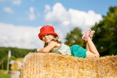 Cute little toddler girl laying on hay stack