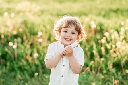Cute little boy looking at the camera smiling sweetly on green meadow