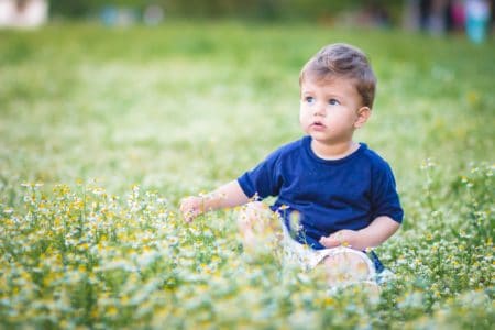 Adorable little blond boy sitting on the grass