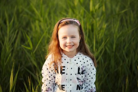 Adorable little girl smiling standing in meadow