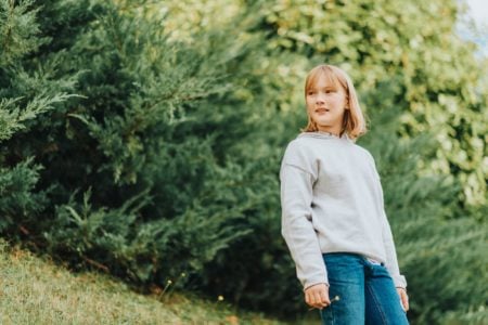 Young little young girl in grey pullover outdoors