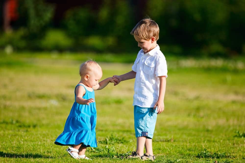 Adorable brother and sister having fun outdoors at sunny day