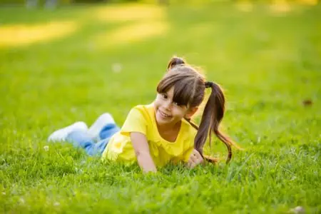 Happy little girl laying on the grass