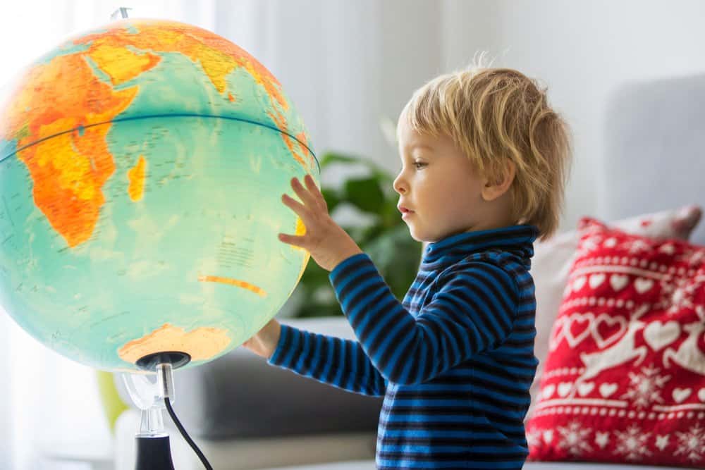 Cute little boy looking at the globe and exploring the world