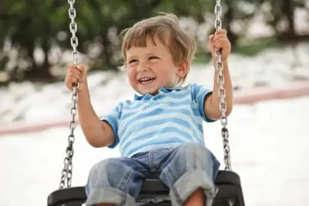 Happy little boy sitting on the swings