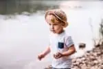 Little Finnish boy playing with rocks on the lake shore