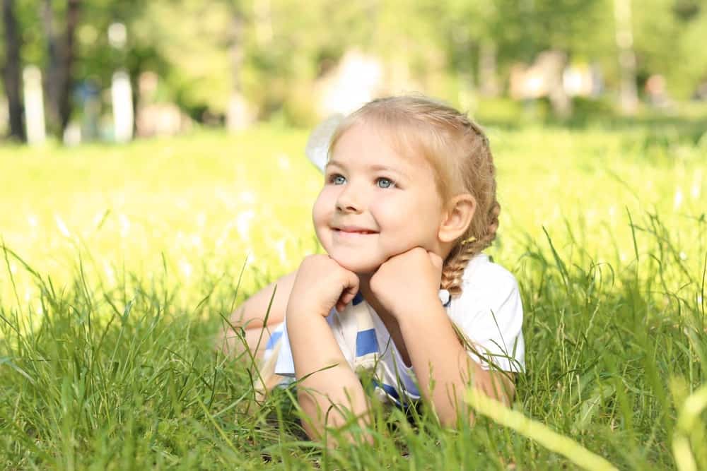 Smiling little girl lying on the grass in the park