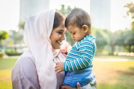 Happy Muslim mother playing with her baby son outdoors