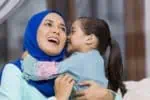 Little Muslim girl kissing her mother on the cheek