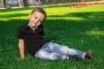 Little boy sitting on the grass in the park