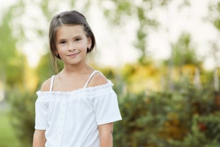Portrait of adorable young girl smiling brightly in the park on sunny day