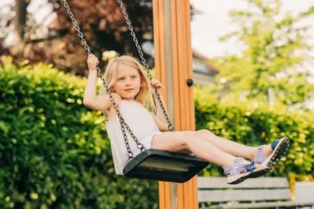 Pretty little blonde girl on swing at the park