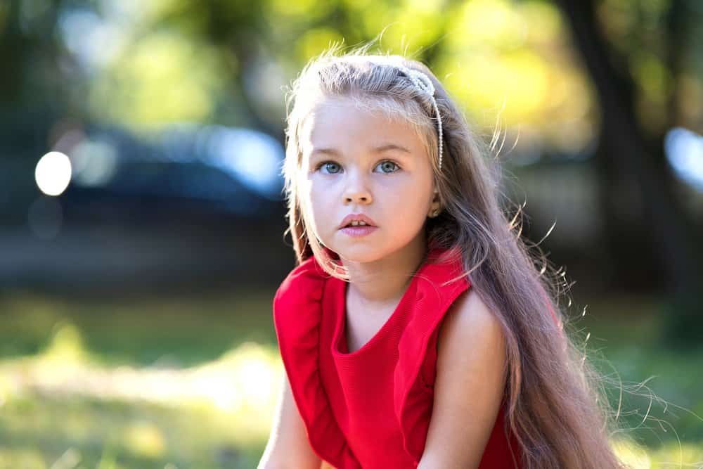 Beautiful young girl in red dress in the park on sunny day