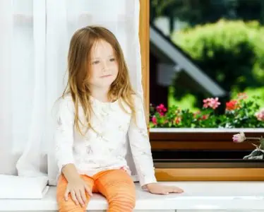 Cute little girl sitting on a bathroom window with glimpse of nature outdoors