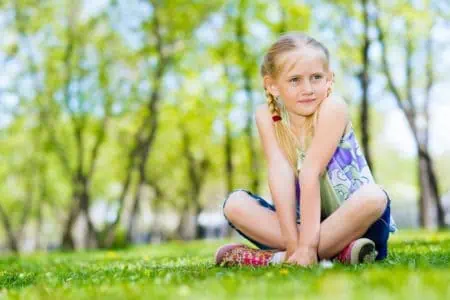 Cheerful girl sitting in the grass on a summer park