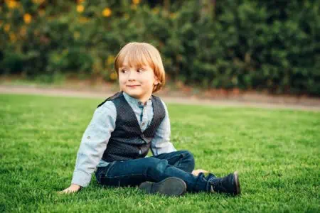 Adorable cute toddler boy sitting in the grass outdoors