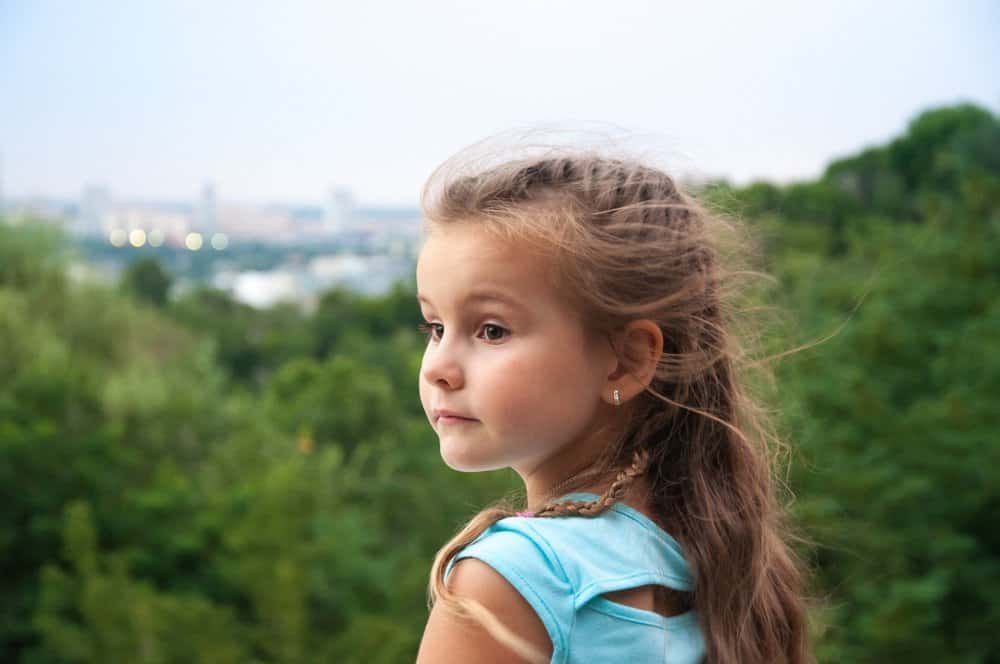 Cute little young girl looking into distance with nature background
