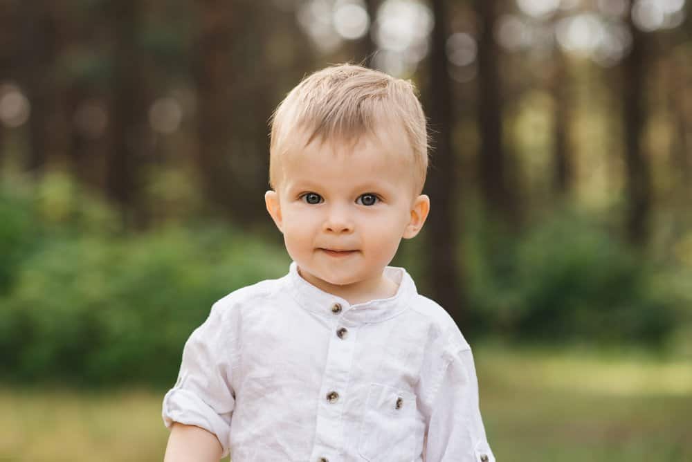 Adorable toddler boy looking at the camera in the forest