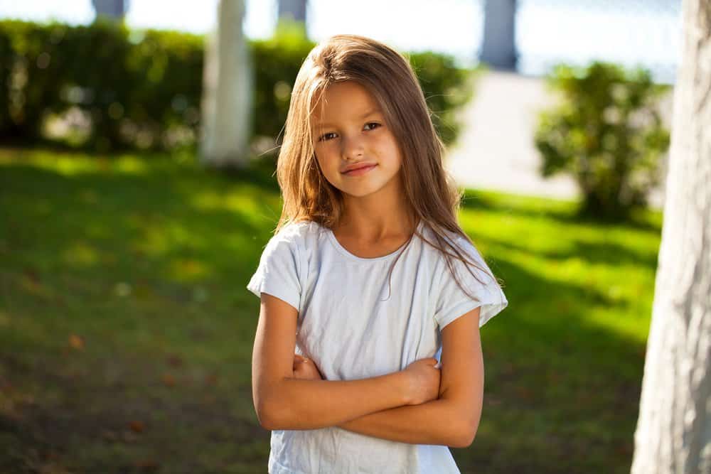 Beautiful brunette little girl posing for the camera on sunny day at the park