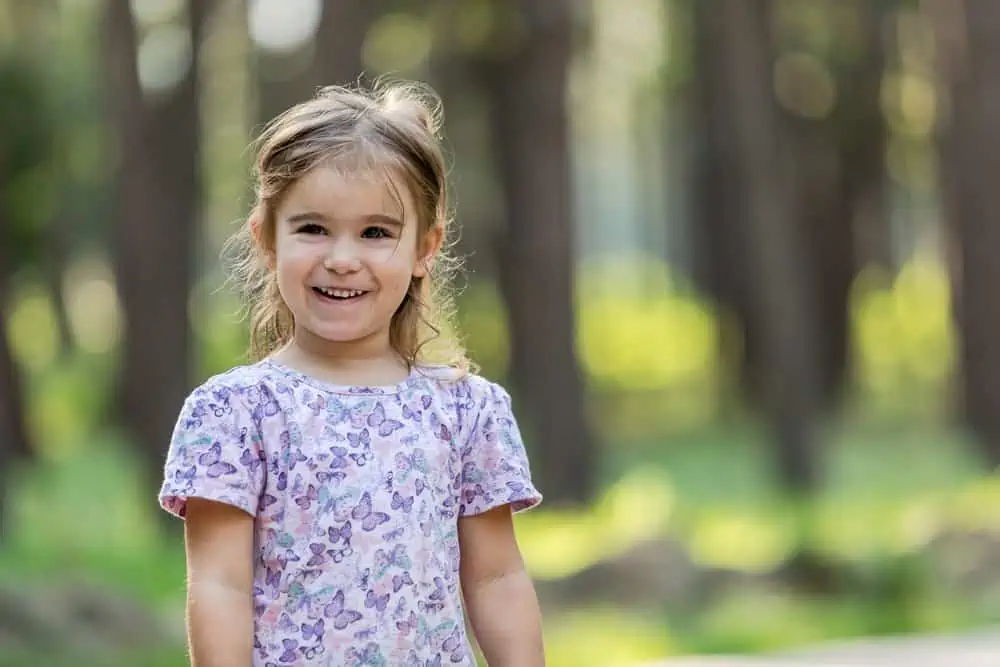 Cheerful little girl having fun in green city park