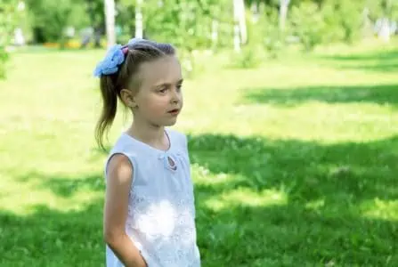 Adorable little girl standing in the park on sunny day