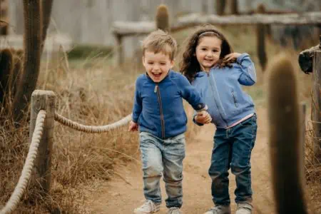Two adorable kids holding hands while running