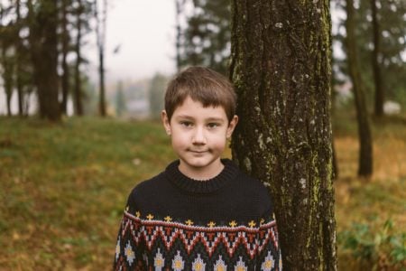 Adorable young boy smiling for the camera in nature background