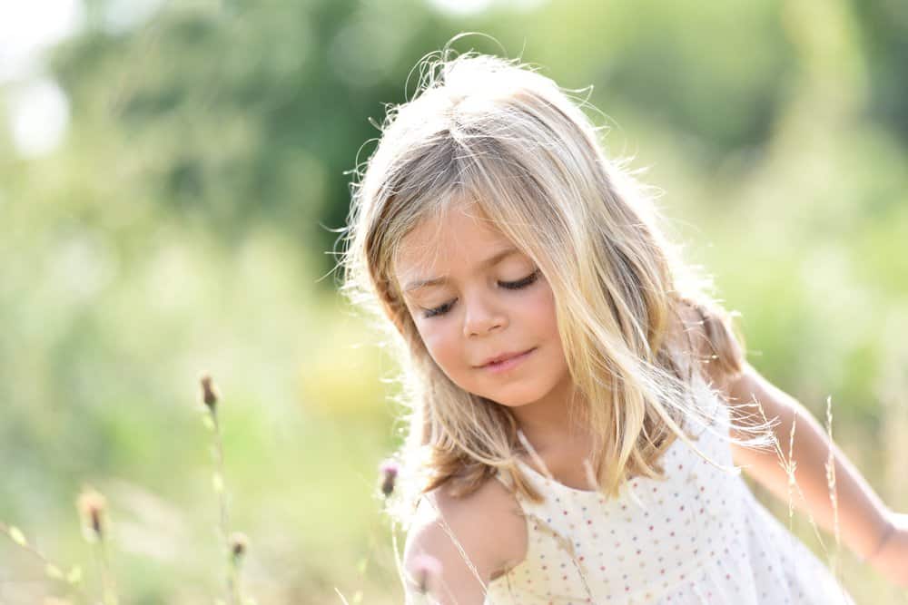 Happy little girl picking flowers in the field