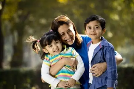 Happy Armenian mother hugging her son and daughter in the park