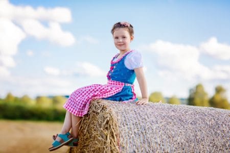 Little German girl in Bavarian costume sitting on a haystack