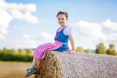 Little German girl in a Bavarian costume sitting on a haystack