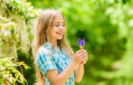 Smiling little girl looking at the iris flower