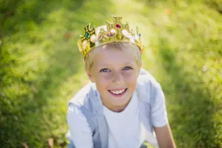 Young boy wearing a crown looking up at the sky
