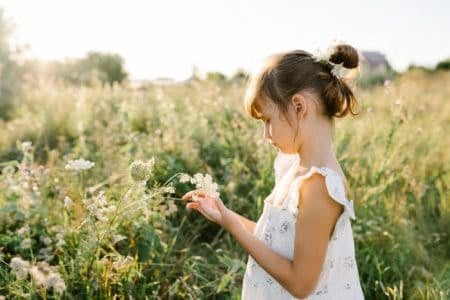 Adorable little girl in dress in the flower field