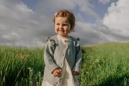 Cute toddler girl in casual clothes in green meadow