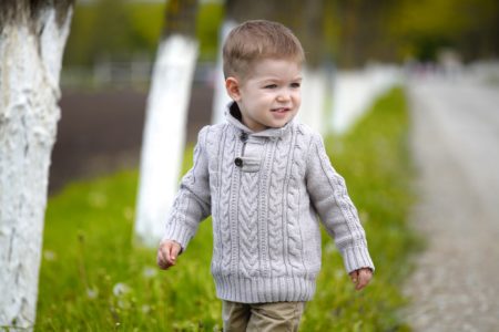 Adorable little toddler boy walking in the park during spring season