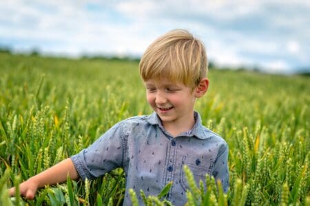 Cheerful blonde little boy in meadow