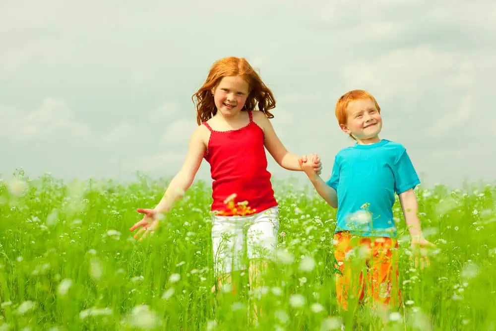 Two kids holding hands and having fun in the field