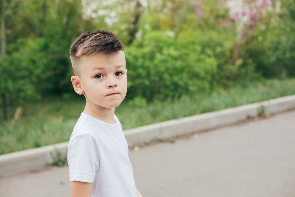 Adorable young boy in white tshirt in the park looking at the camera
