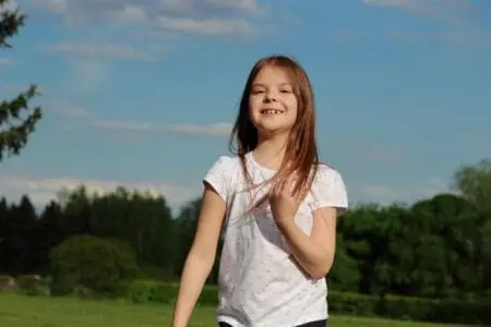 Cheerful young girl wearing white tshirt playing in the park