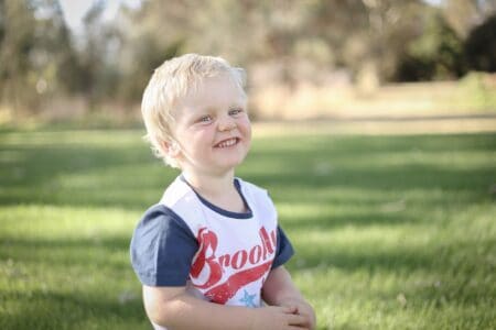 Cute caucasian boy with blue eyes smiling happily in the park