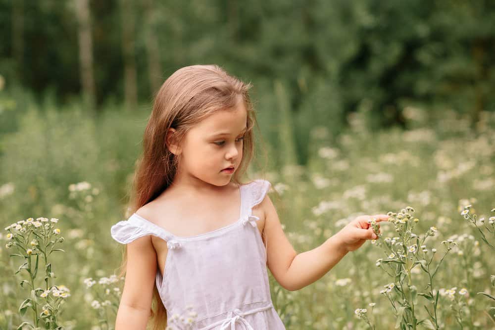 Beautiful little girl in white dress in the meadow