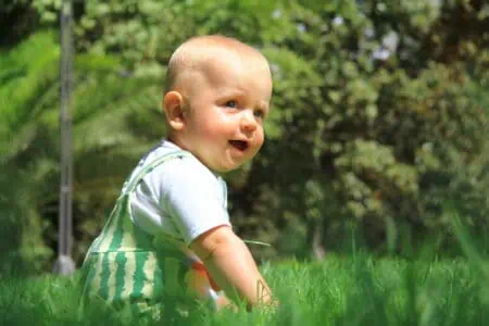 Adorable baby boy sitting on the grass at the park