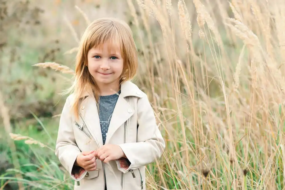 Adorable blonde little girl smiling in the meadow