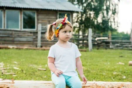 Pretty little girl sitting on fence in the backyard