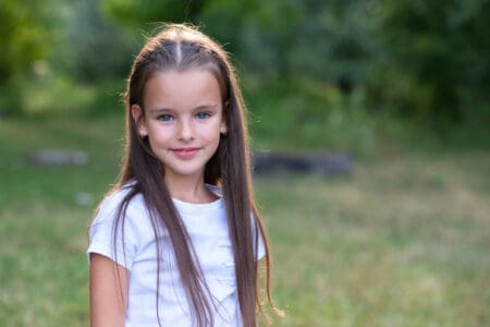 Pretty little girl with long brown hair posing summer nature outdoor