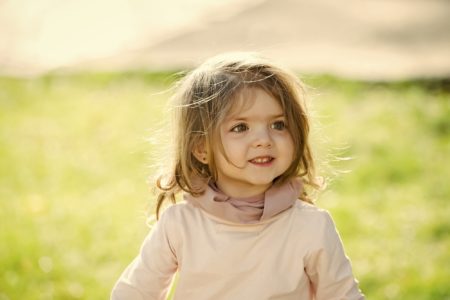 Cute toddler girl smiling brightly on sunny day at the park